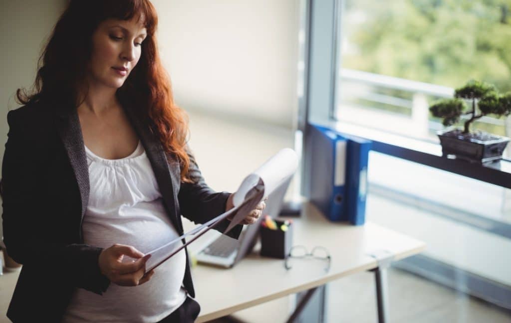 Pregnant traveller reviewing pregnancy travel insurance documents before flying