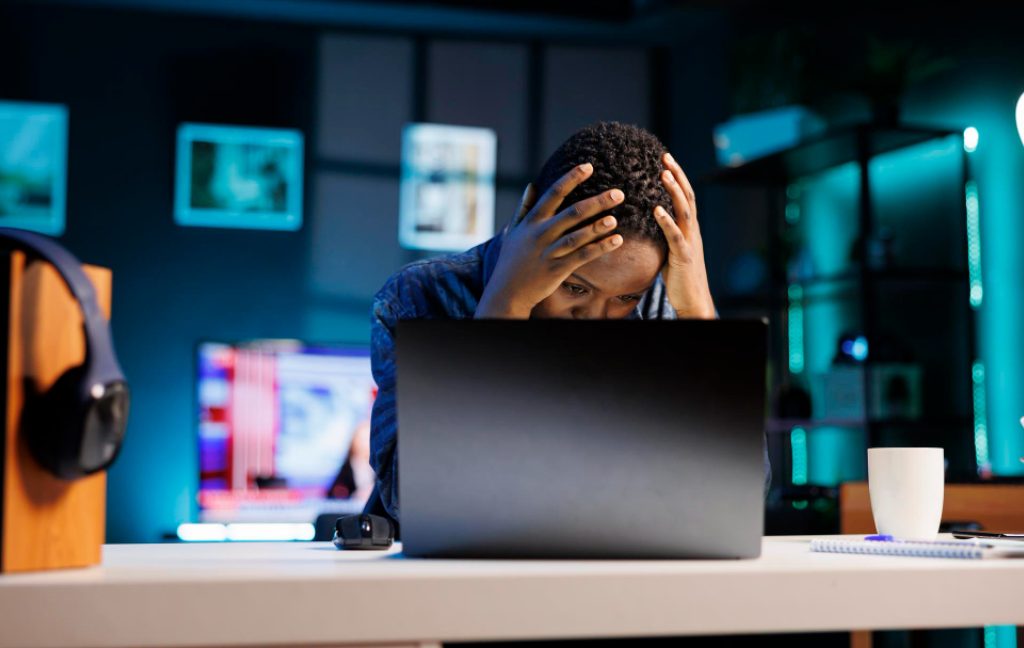 Remote worker looking frustrated at a laptop due to poor internet during a workcation.
