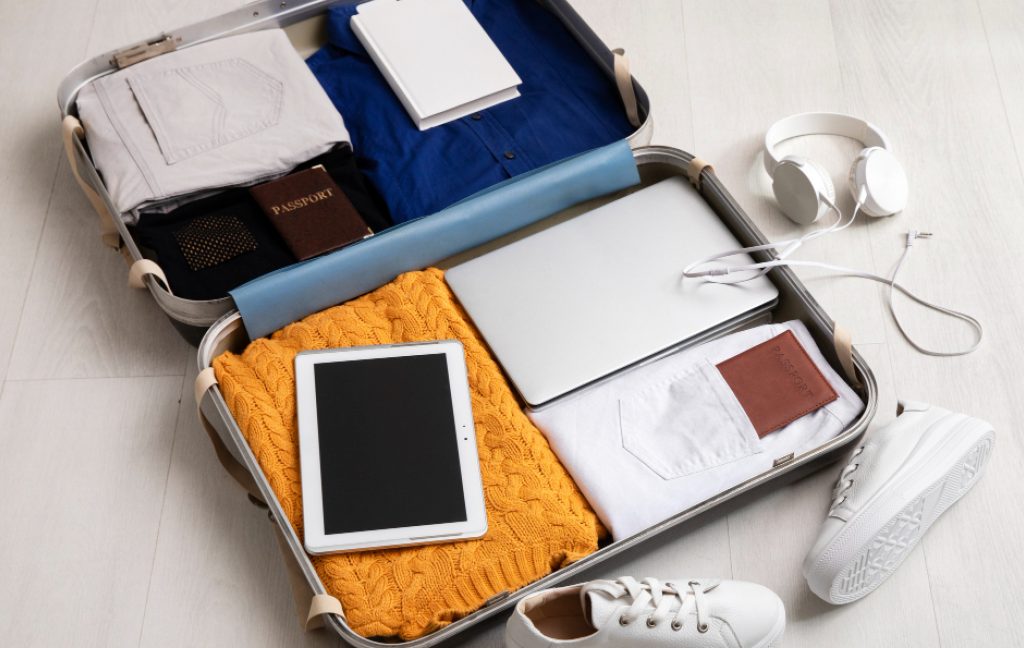 Open suitcase packed with work essentials for a workcation.